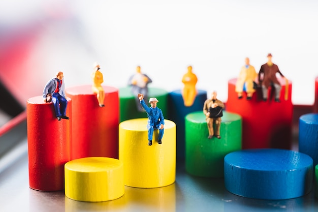 Miniature people sitting on colorful wooden block using as family and social concept