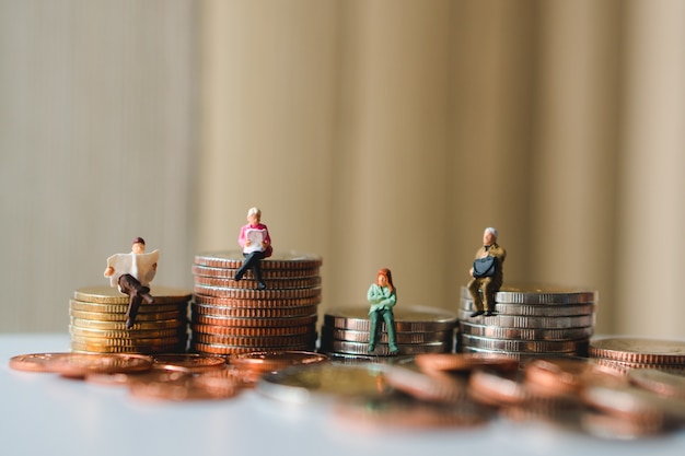 Miniature people sitting on stack coins using as business, finance and social concept