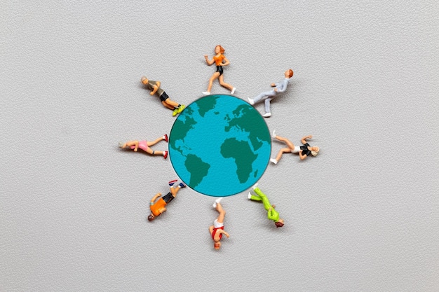 Miniature people standing on the globe with gray background