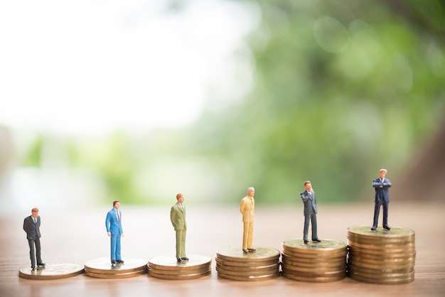 Miniature people standing on stack of coin