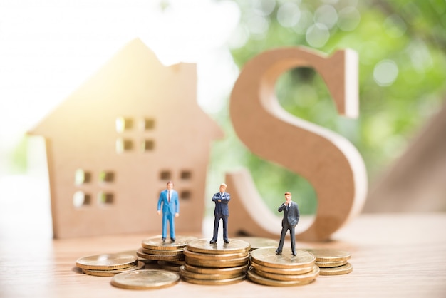 Miniature people standing on stack of coin