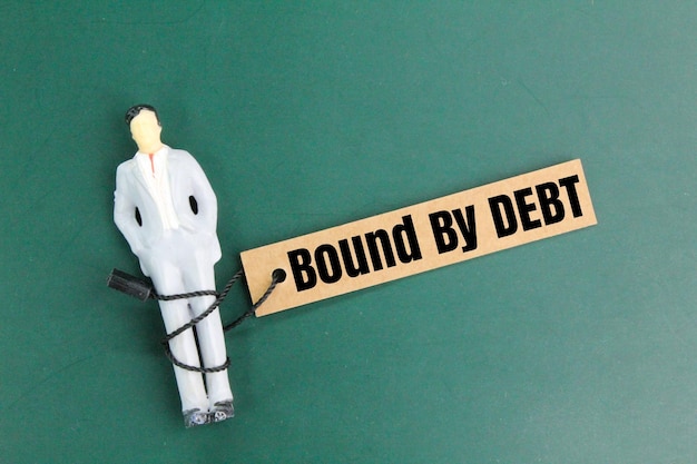 miniature people surrounded by the word bound by debt the concept of being indebted or bound by deb