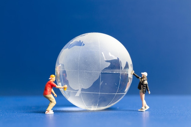 Miniature people Teenager spraying paint crytal globe on blue background World environment day concept