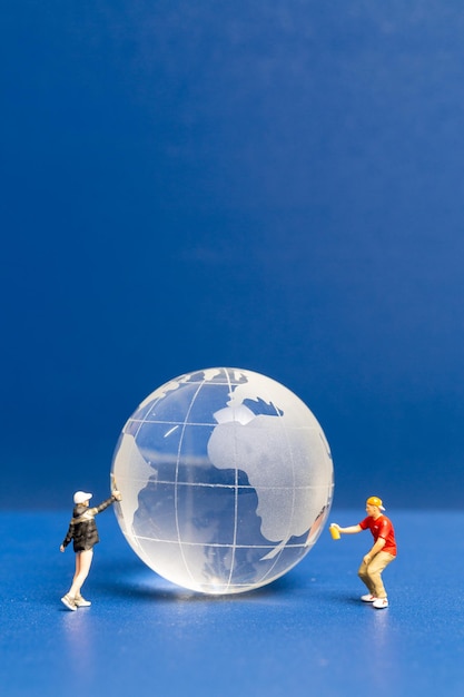 Miniature people Teenager spraying paint crytal globe on blue background World environment day concept