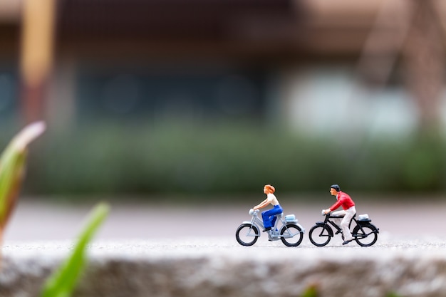 Miniature people travellers with bicycle in the park