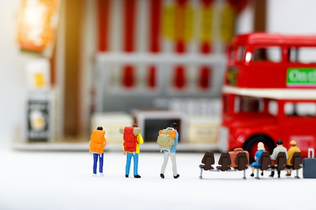 Miniature people with baggage waiting for bus. Transportation.