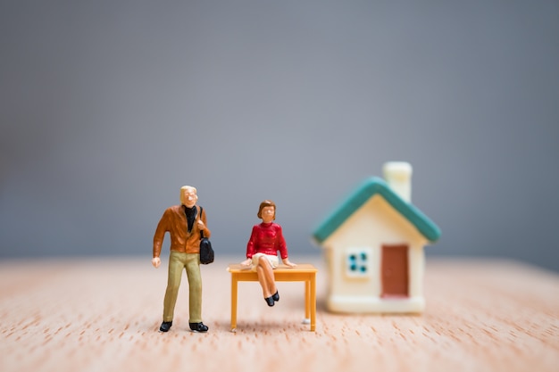 Miniature people, woman and man stay in front of house, use for business teamwork concept