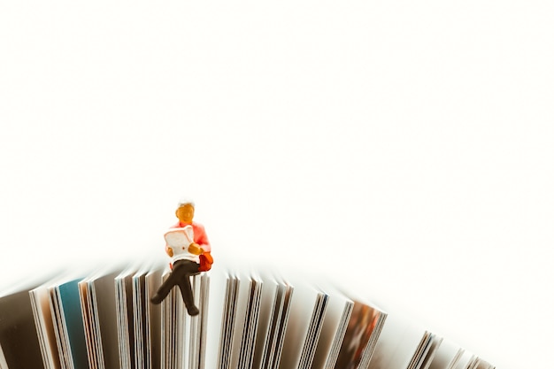 Miniature people,woman sitting on paper using as education and social background concept