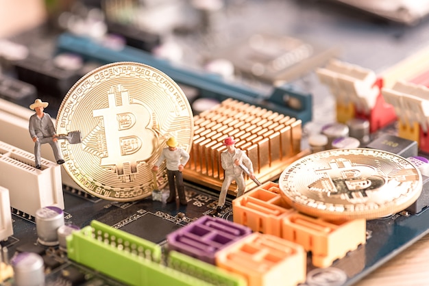 miniature people worker digging bitcoin on computer mainboard 