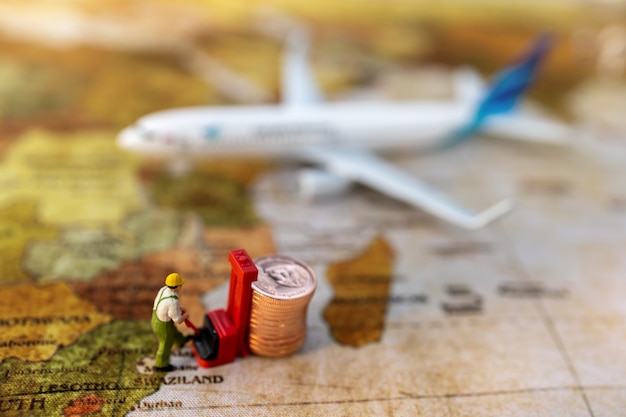 Miniature people:  Worker loading coins  to plane. Shipping and online delivery service concept.