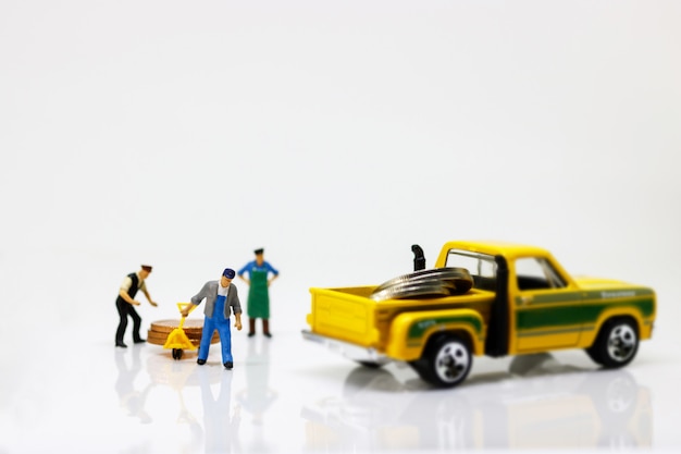 Miniature people: Worker move coins stack to car.