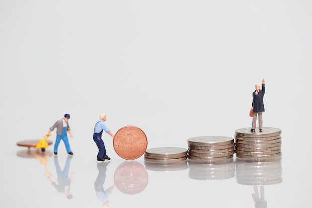 Miniature people: worker with coin and businessman , business concept using as background