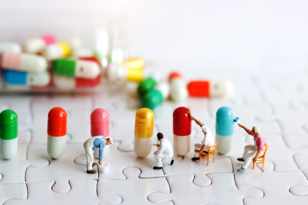 Miniature people: Workers  team brush painting Medicinal capsules. Healthcare, Medical  and business concept.