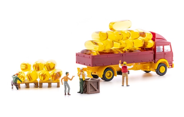 Miniature people workers transportation fish oil supplement capsules by truck isolated on white background, health care and medical business concept.