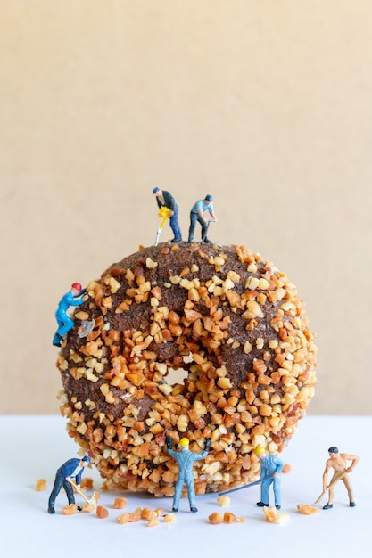 Miniature people working team making homemade chocolates butternut donuts