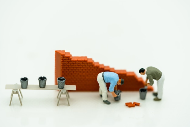 Miniature people working on a wall