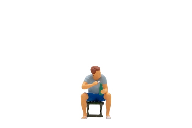 Miniature people Young man sitting on a lawn chair isolated on white background