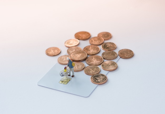 Miniature shoppers with shopping cart on a credit card or debit card