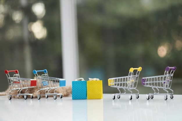 Miniature shopping cart on wooden mock up over blurred green garden on day noon light Image for Shopping online concept