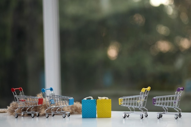 Miniature shopping cart on wooden mock up over blurred green garden on day noon light Image for Shopping online concept