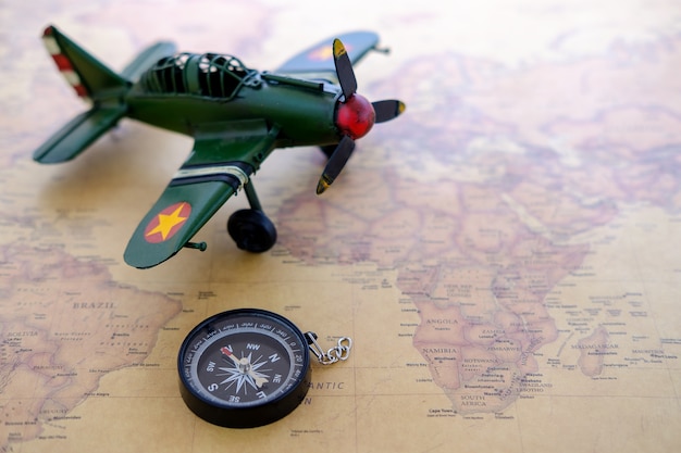 Miniature tourist on compass with plastic toy airplane 