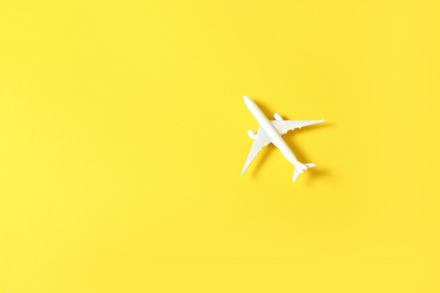 Miniature toy airplane on yellow background. Trip by airplane.