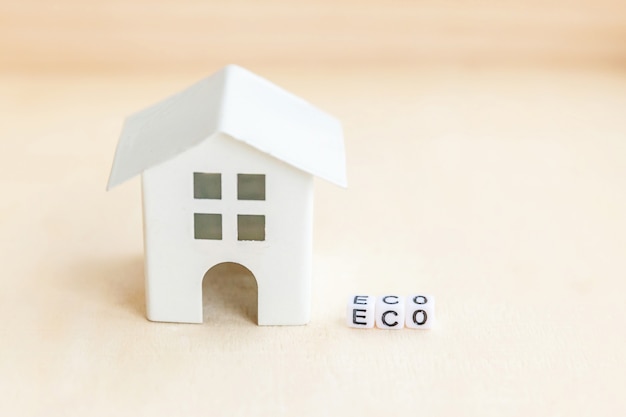 Miniature toy model house with inscription ECO letters word. Eco Village, abstract environmental background. Ecology zero waste social responsibility recycle bio home concept