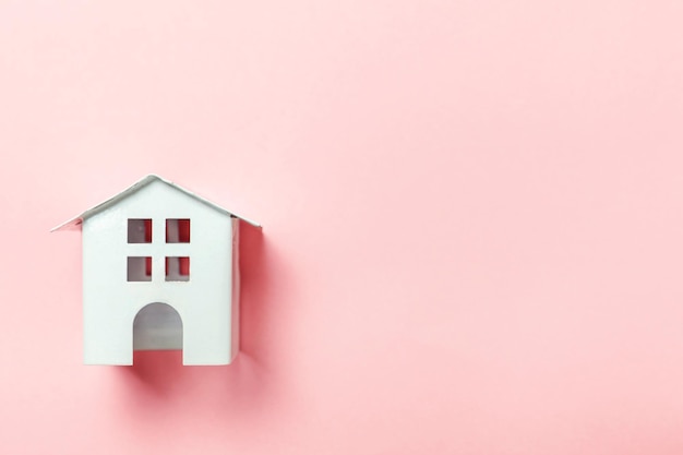 Miniature white toy house on pink pastel background