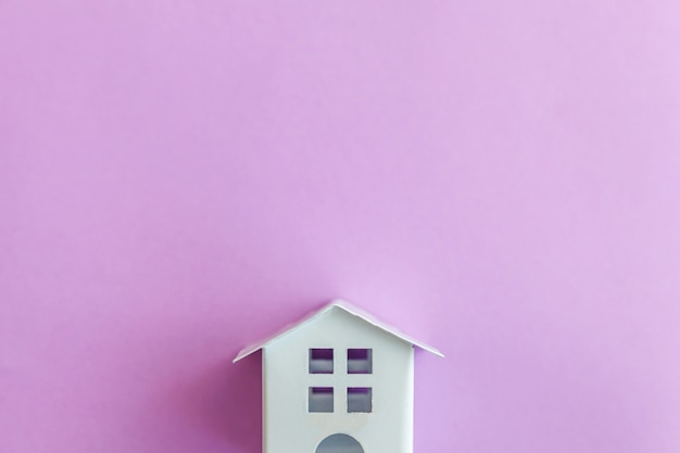 Miniature white toy house on purple violet pastel background