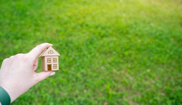 Miniature wooden house in the female hand outdoors Real estate concept Ecofriendly home Buying a housing outside the city Copy space