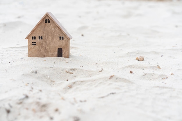 Miniature wooden house model on sand background concept for travel vacation real estate investment