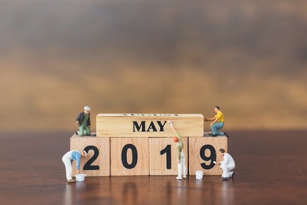 Miniature worker team painting  on wooden block 