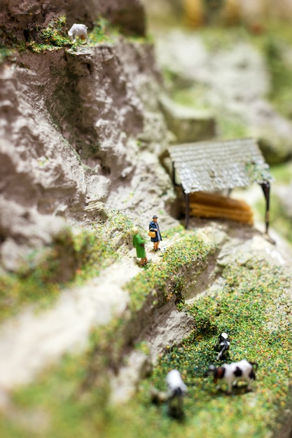 Miniature world with two woman standing on a mountain path and talking near grazing cows