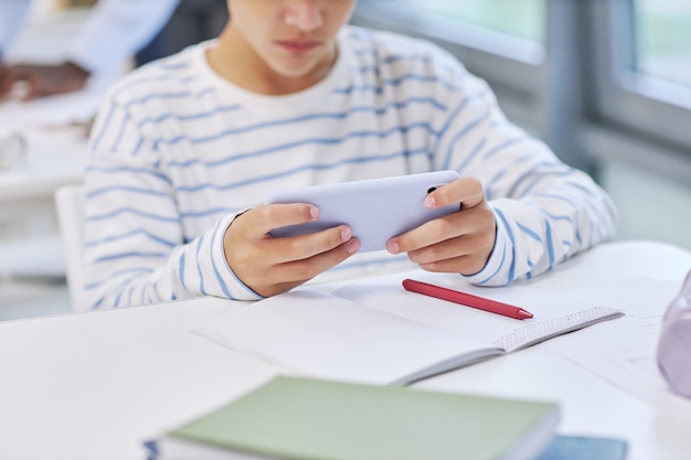 Minimal close up of child holding smartphone and playing mobile game in school