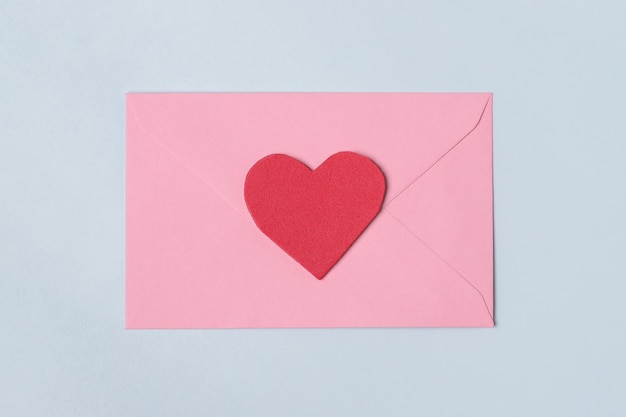 Minimal composition with a pink envelope with red heart for valentine day