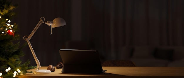 Minimal and cozy home workspace at night with portable tablet tabnle lamp and Christmas tree