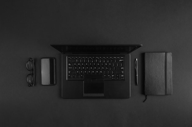 Minimal flat lay on modern businessman black desk with laptop. Abstract office creative concept.