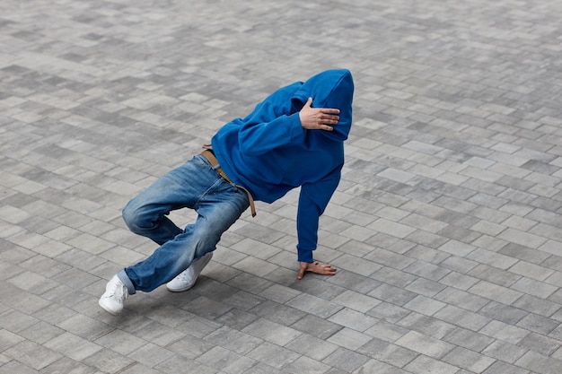 Minimal high angle shot of male hiphop dancer performing in street with tile background copy space