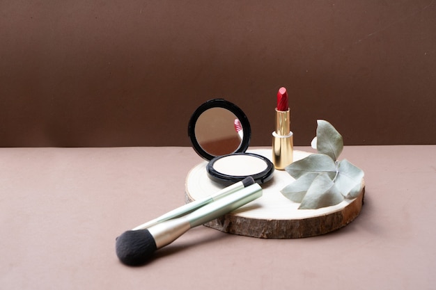 Minimal modern cosmetic scene with make up brushes, powder, lipstick, neutral beige background