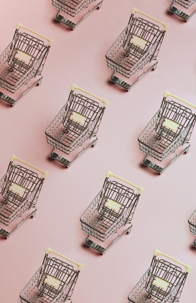 Minimal patter of shopping cart over a pastel pink background, e commerce, online buying, online commerce, background, technology, shopping day, black friday and network