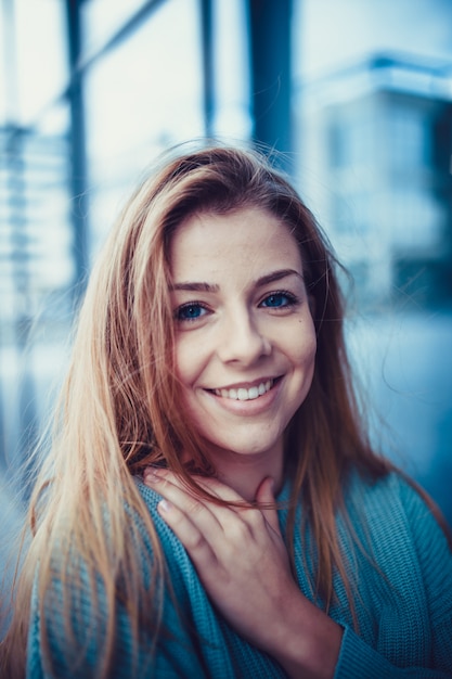 Minimal portrait of a beautiful young girl standing against blue wall