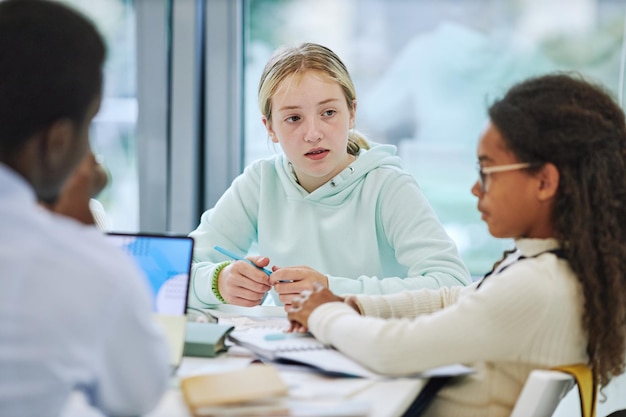 Minimal portrait of young teenage girl in group activity at school listening to classmates