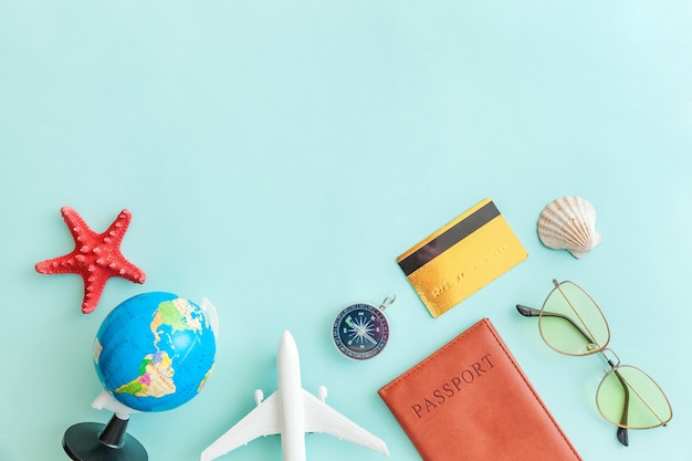 Minimal simple flat lay with plane passport sunglasses globe gold credit card and shell on blue pastel colourful trendy Tourist essentials Copy space