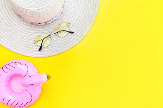 Minimal simple flat lay with sunglasses hat and Inflatable flamingo isolated on yellow