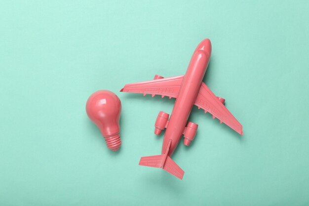 Minimal travel layout Pink plane and light bulb on mint blue background Fresh idea Flat lay Top view