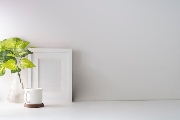 Minimal workplace with flower pot and picture frame on white table Home office Copy space for text