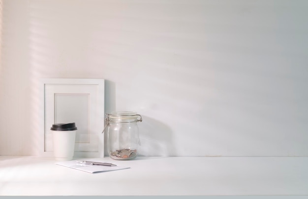 Minimal workplace with picture frame notebook and coffee cup near window with sun shade roller blind