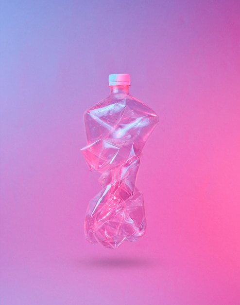 Minimalism pollution ecology concept. Crumpled plastic bottle in neon red blue light