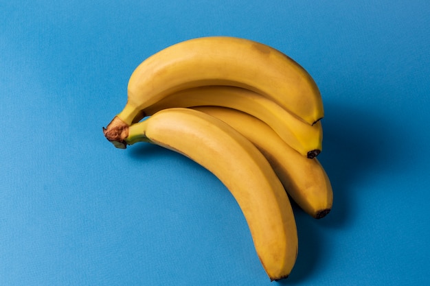 Minimalism style. Fruit pattern with yellow ripe banana fruit over blue background.