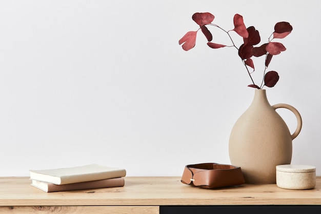 Minimalist concept of living room interior at elegant apartment with wooden commode, leaf in ceramic vase and elegant personal accessories in modern home decor. Copy space.. .